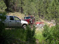 Log truck barreling down the road next to the stream, back for another load of big pondorosa pines