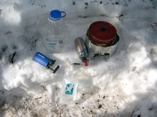 A light kitchen and water maker for three. Note that the snow is just melted and then filtered, not boiled, saving coleman costs. MSR Dragonfly stove, pot and heat exchanger, Nalgene and Platypus bags, and Katadyn Mini filter.